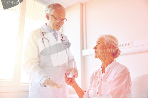 Image of doctor giving medicine to senior woman at hospital