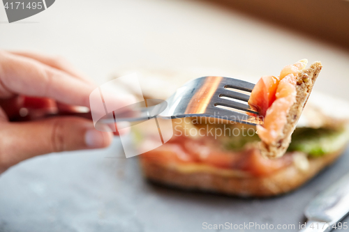 Image of woman eating salmon panini sandwich at restaurant