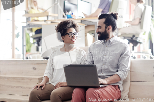 Image of happy creative team with laptop in office