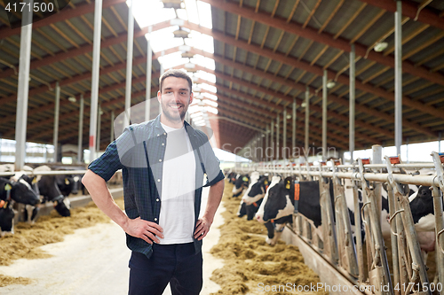 Image of man or farmer with cows in cowshed on dairy farm