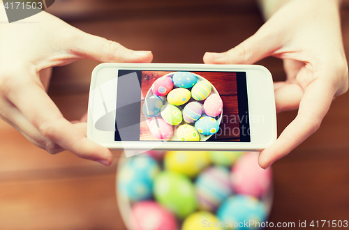 Image of close up of hands with easter eggs and smartphone