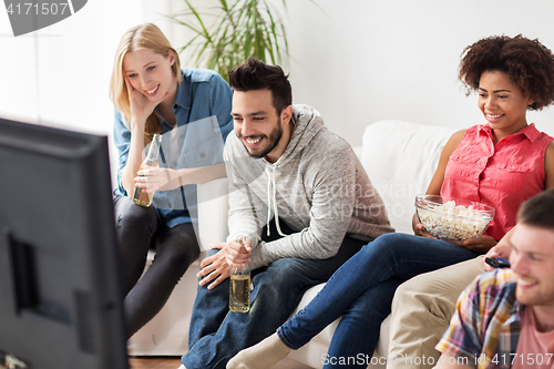 Image of happy friends with popcorn watching tv at home