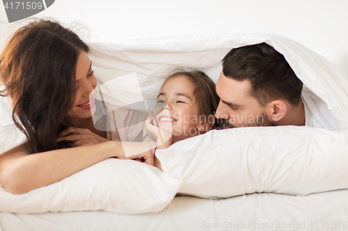 Image of happy family lying in bed under blanket at home