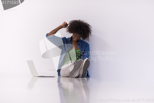 Image of african american woman sitting on floor with laptop