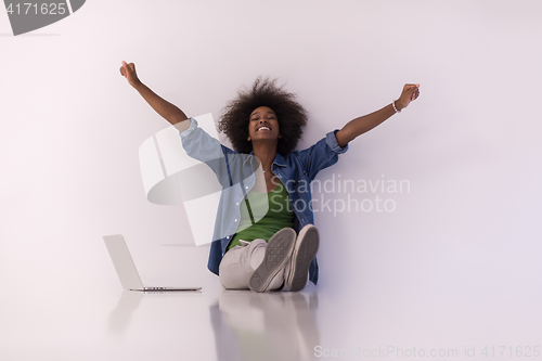 Image of african american woman sitting on floor with laptop