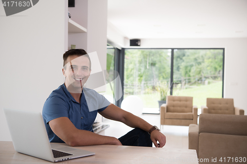 Image of Young man with laptop at home