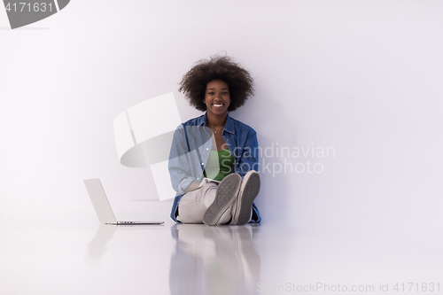 Image of african american woman sitting on floor with laptop