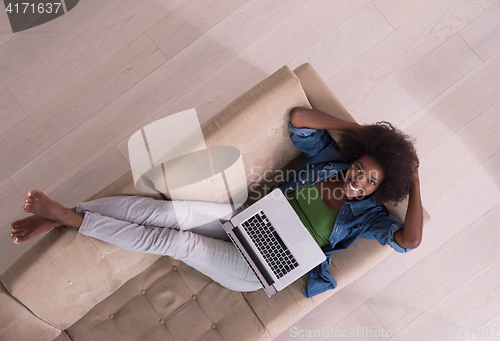 Image of African American woman using laptop on sofa top view