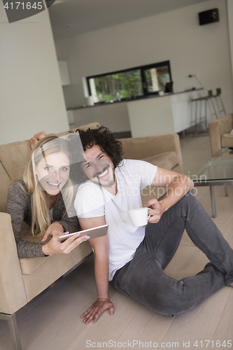 Image of couple relaxing at  home with tablet computers