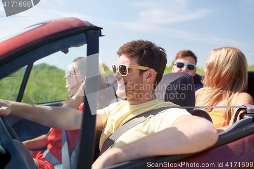 Image of happy friends driving in cabriolet car