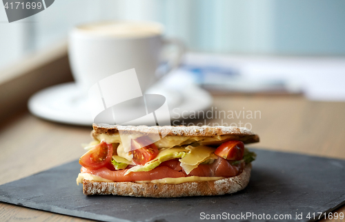 Image of salmon panini sandwich on stone plate at cafe