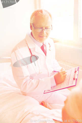 Image of senior woman and doctor with clipboard at hospital