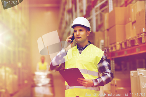 Image of man with clipboard and smartphone at warehouse