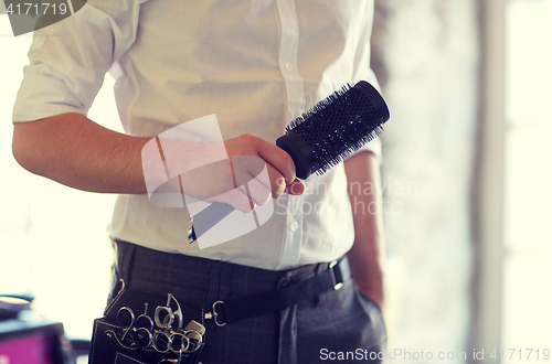 Image of close up of male stylist with brush at salon