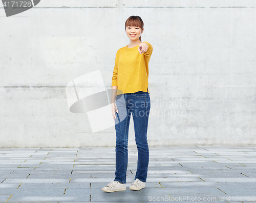 Image of happy asian young woman pointing finger on you