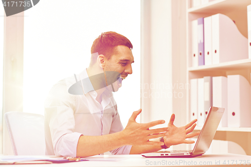 Image of angry businessman with laptop and papers in office