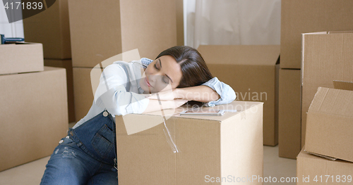 Image of Young woman taking a nap on a brown carton