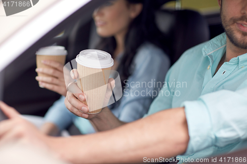 Image of close up of couple driving in car with coffee cups