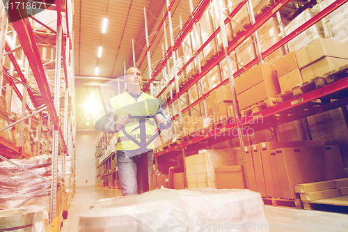 Image of man carrying loader with goods at warehouse