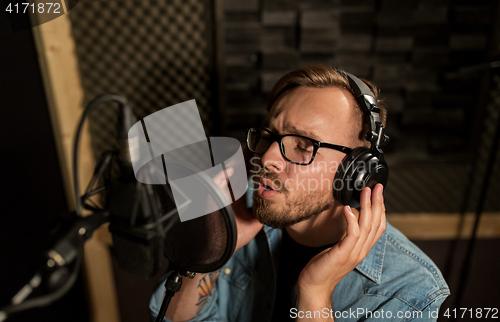 Image of man with headphones singing at recording studio