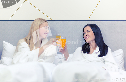 Image of smiling girlfriends having breakfast in bed