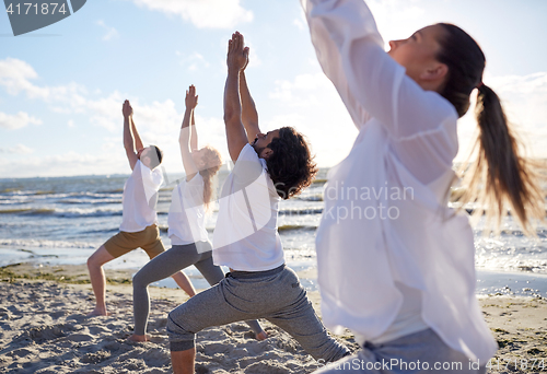 Image of group of people making yoga exercises on beach