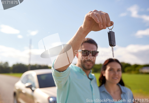 Image of happy man and woman with car key outdoors