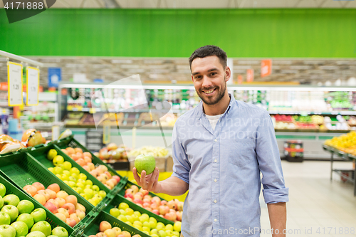 Image of happy man buying green apples at grocery store