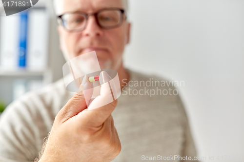 Image of close up of old man hand with pill