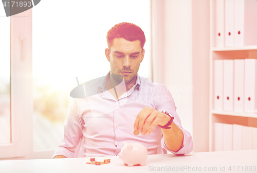 Image of businessman with piggy bank and coins at office