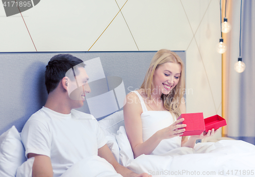 Image of smiling couple in bed with red gift box