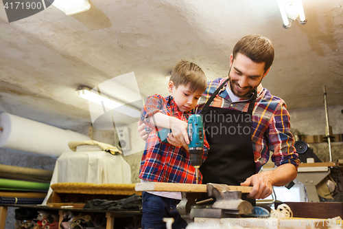 Image of father and son with drill working at workshop