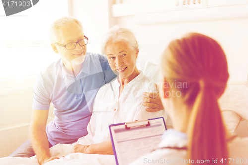 Image of senior woman and doctor with clipboard at hospital