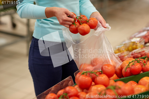 Image of woman with bag buying tomatoes at grocery store