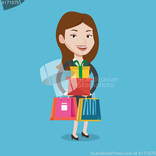 Image of Happy woman holding shopping bags and gift boxes.
