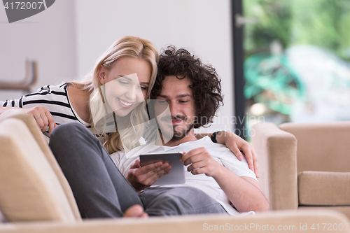 Image of couple relaxing at  home with tablet computers