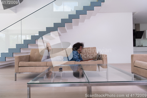 Image of African American woman using laptop on sofa