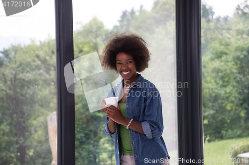 Image of African American woman drinking coffee looking out the window