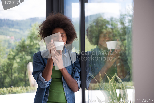 Image of African American woman drinking coffee looking out the window