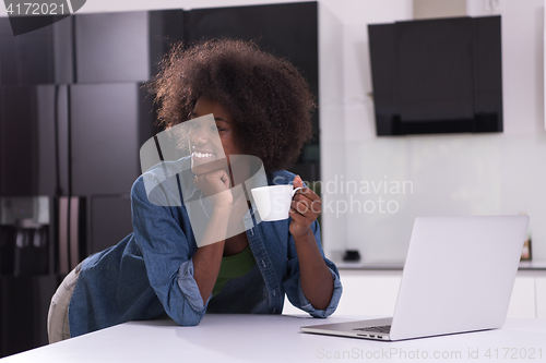 Image of smiling black woman in modern kitchen