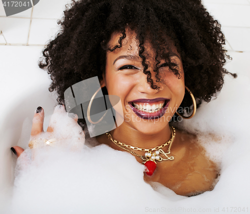 Image of young afro-american girl in a black bikini sitting in bath, wear