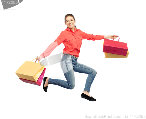 Image of smiling young woman with shopping bags jumping