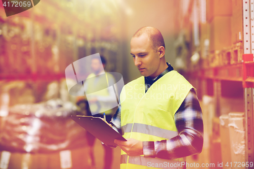 Image of man with clipboard in safety vest at warehouse