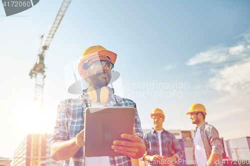 Image of builder in hardhat with tablet pc at construction