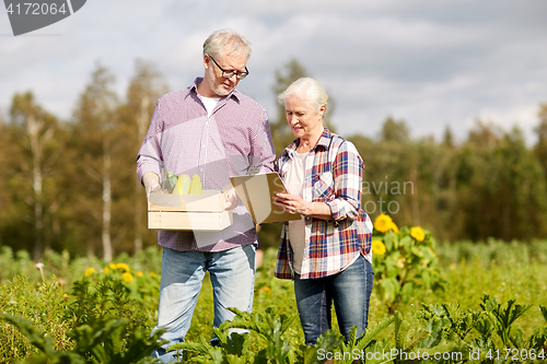 Image of senior couple with box of vegetables at farm