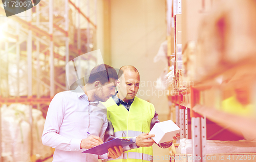 Image of worker and businessmen with clipboard at warehouse