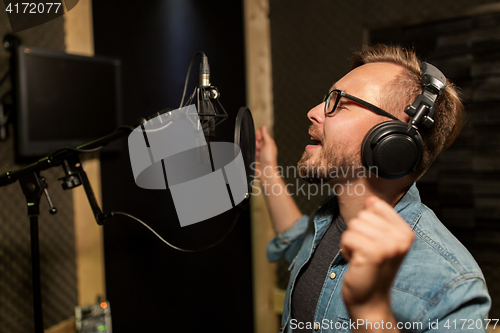 Image of man with headphones singing at recording studio