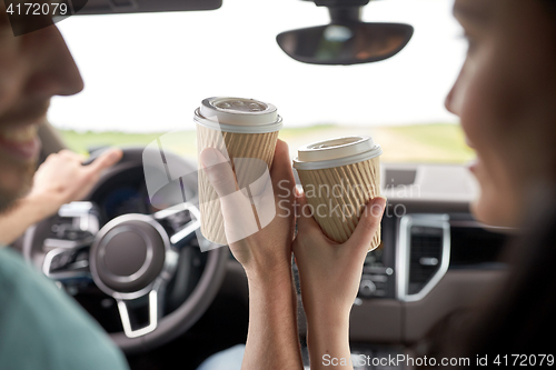 Image of close up of couple driving in car with coffee cups