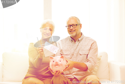 Image of senior couple with money and piggy bank at home