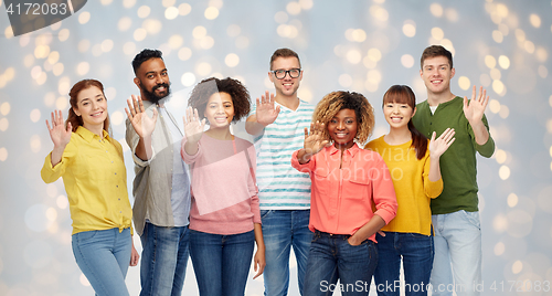 Image of international group of happy people waving hand